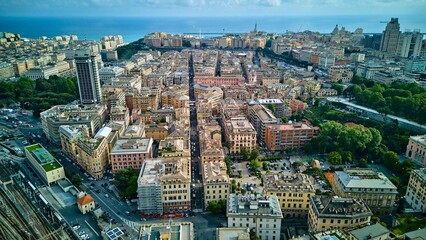 Aerial drone view looking down a central street in Genoa, Italy, towards the Ligurian Sea