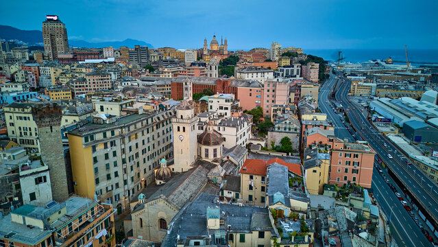 Drone view of Genoa's historic churches Santa Maria Assunta and Chiesa di Santa Maria di Castello and the elevated highway in Italy. An aerial shot of the city's diverse architecture by the sea.