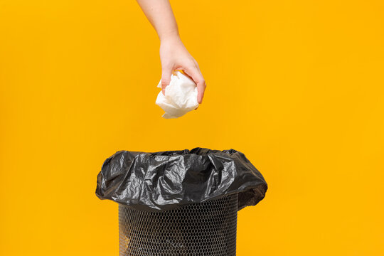 Woman throwing napkin into trash bin on orange background, closeup
