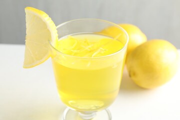 Yummy yellow jelly in dessert bowl and lemons on white table, closeup