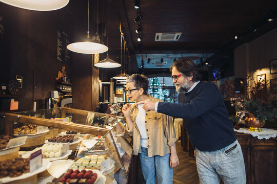 Mature couple choosing desserts in artisan bakery