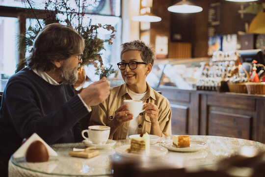 Mature couple enjoying coffee and cakes at cafe