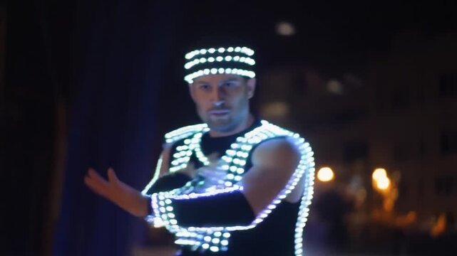 Performer in illuminated LED costume dancing at night in closeup