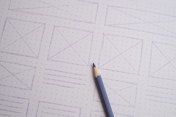 High-Angle Flat Lay of Hand-Drawn Website and App Wireframes on Grid Paper with Colored Pencils