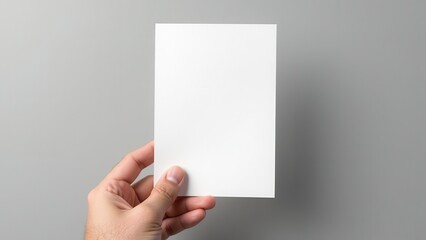 Obraz premium A5 Flyer / Invitation Mock-Up – Male Hands Holding Blank Flyer on Gray Background