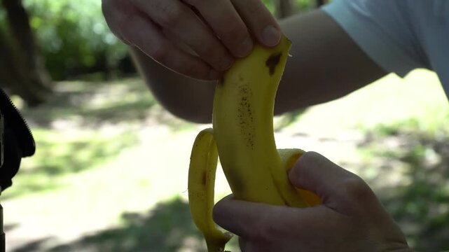 A man gently peels a banana, ready to take a bite.
