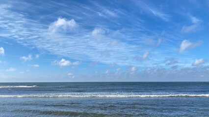 Calm Ocean and Blue Sky with Soft Clouds Background