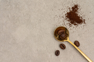 Ground coffee in golden spoon on neutral background, top view