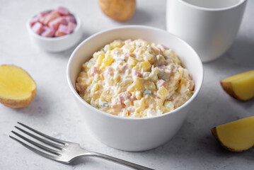 Ham and potato salad in a bowl on a white background