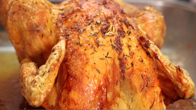 Gros plan sur un poulet r&ocirc;ti dor&eacute; sortant du four.