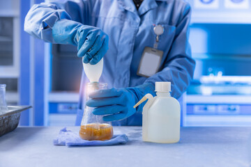 Fototapeta premium Laboratory technician pouring reagent into flask on bench