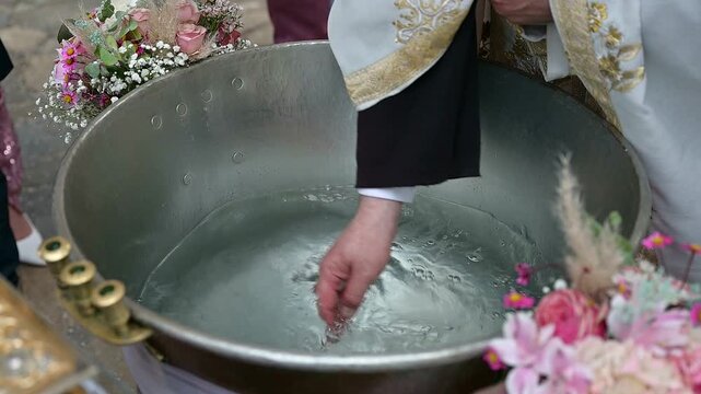 Priest blesses water for baby baptism