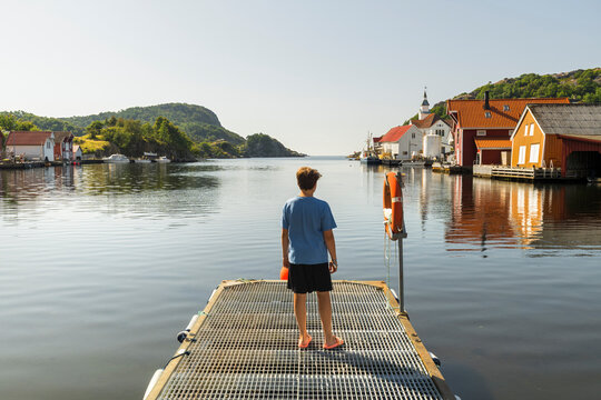 Junge steht auf einem Steg in Kirkehamm, Hidra, Vest Agder, Norwegen
