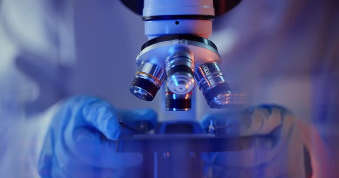 Medical laboratory work, scientist use Microscope gloved hands adjustment focus sequence showing progressive lens positioning and slide handling.