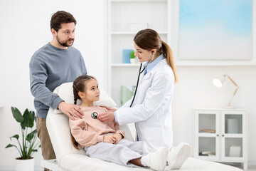 Obraz premium Little girl and her father having appointment with pediatrician in hospital. Doctor checking child with stethoscope