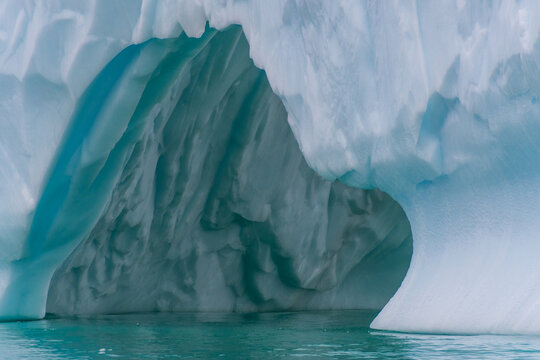 An Antarctic landscape shot near Cuverville island, highlighting mountains and icebergs.