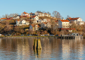 Obraz premium Hillside residential neighborhood by water on clear day.