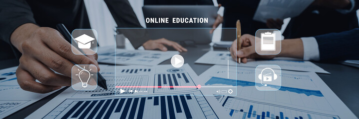 Professionals engage in a collaborative online education project, analyzing data charts and planning documents in a modern workspace for effective learning. Trope © InfiniteFlow