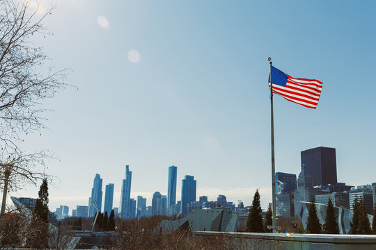 City skyline with American flag waving in the wind during a clear day with no clouds visible in the sky