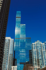 Fototapeta premium Sky high building stands among city skyscrapers under clear blue sky