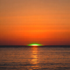 Fototapeta premium Rare green flash appearing at ocean sunset, calm sea and clear horizon, warm orange sky with brief green light, realistic atmospheric phenomenon, natural and serene seascape.