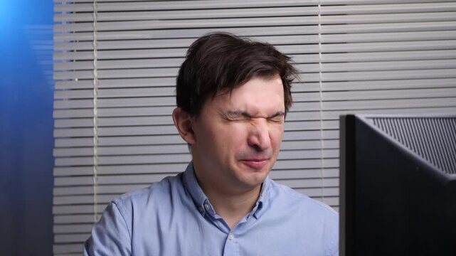 Man yawning at his desk, hand over mouth, eyes closed exhausted office worker battling sleepiness and fatigue while sitting before a computer after long hours of work