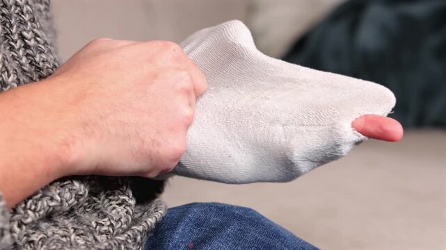 Une personne montrant un trou dans une chaussette.