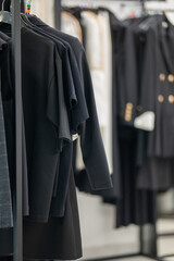 Black clothing hanging on metal racks in a modern retail store.