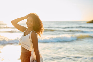 Naklejka premium Smiling young woman enjoying a beach vacation, with sun setting over ocean waves, symbolizing happiness and freedom