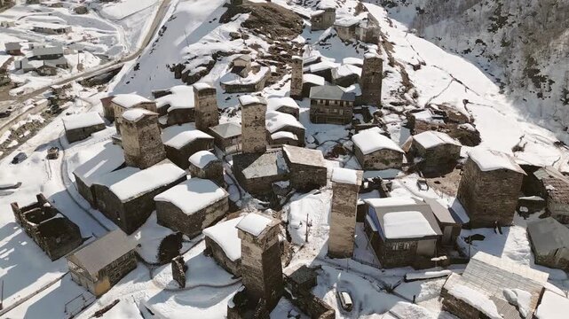 Aerial panorama Ushguli village snowy rooftops under bright sun snow covered mountains, UNESCO World Heritage Site in Svaneti Georgia. Chazhashi - most preserved village with svan towers