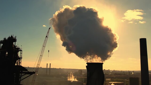 Dark factory chimney releasing thick grey coal smoke polluting air and environment. Industrial plant emits emissions from coal combustion. Heavy industry fossil fuel pollution environmental damage