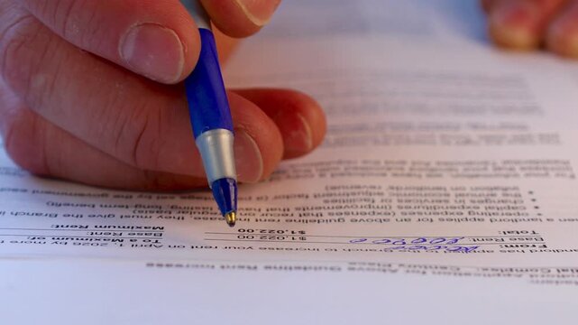 Hand Signing Paper Form Closeup.hand holding blue pen marking checkboxes on tax form document, concept of financial reporting, filing, audit and personal income declaration.