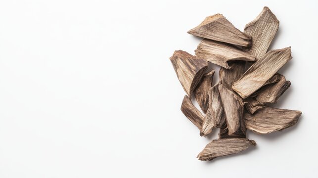 Aromatic oud wood chips scattered naturally on a stark white background for fragrance