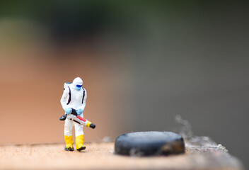 Macro of miniature hazardous materials workers extinguishing a fire, dramatic lighting, dark background, and detailed swirling smoke.