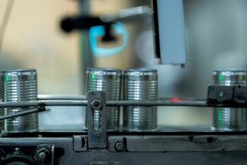 Fototapeta premium Close up of metal cans on automated conveyor belt in food processing plant. Industrial manufacturing machinery packaging line for commercial distribution product.