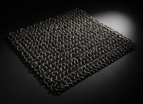 Intricate metal chainmail fabric on dark background