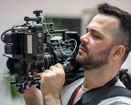 A male videographer holding a heavy professional cinema camera rig on his shoulder, ready for filming.