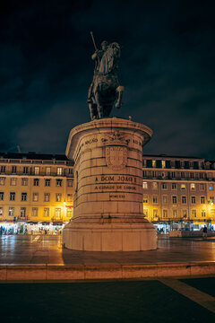 Low angle shot of a majestic bronze statue on a pedestal, set against a dark night sky in a city plaza.