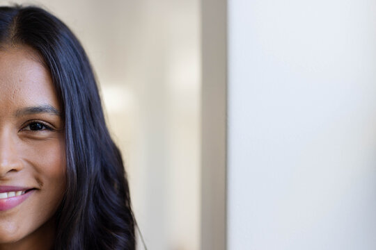 Left half of woman's face is showing soft smile, long hair falling over shoulder, copy space