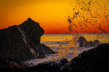 早朝の海で岩を砕く波