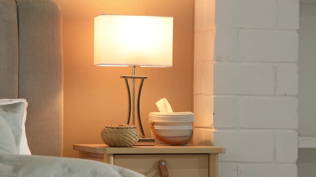 Lamp turning on bedside table at home