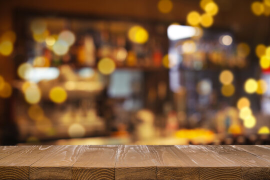 Empty wooden bar countertop against blurred shelves with alcohol