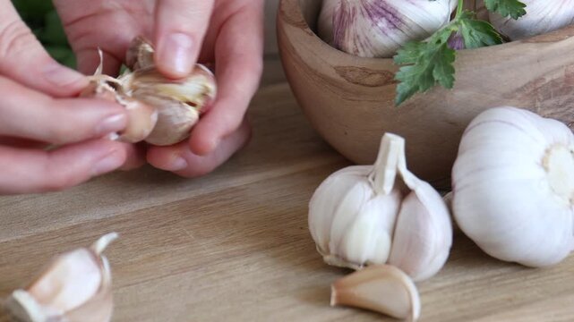 Woman peeling fresh garlic at wooden table, closeup