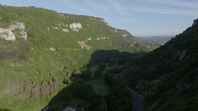 Deep valley of Gorges du Tarn seen from an aerial perspective with shadows stretching across the forest. Drone footage reveals the scale of the canyon and rocky escarpments in the Aubrac region.