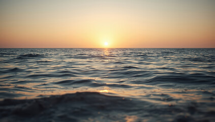 Obraz premium Calm sea sunset with gentle waves and warm sky glow