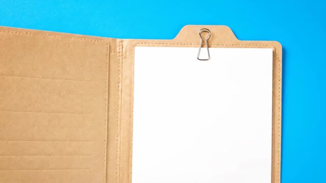 Open manila folder with blank white paper and binder clip on bright blue background