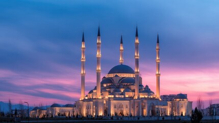 Obraz premium A grand mosque with multiple slender minarets rises against a vibrant sunset sky, bathed in warm evening light