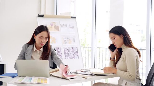 Young asian female interior designer or architect working on creative project with drawing, material sample , laptop computer in office. Business of Real estate, home decoration , renovation concept.