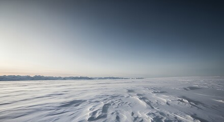 Obraz premium Arctic tundra panorama featuring windswept textured snow sastrugi covering the plain extending toward distant majestic mountain peaks under a deep blue sky