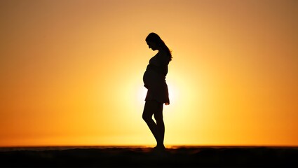 Expecting Mother Silhouette at Sunset on the Beach with Warm Sky